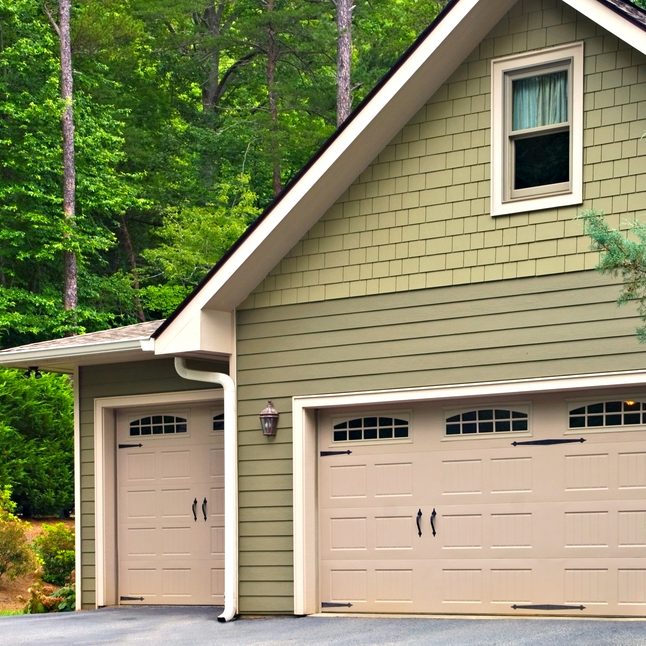 Garage doors on a modern house.  Double doors with windows on one side and an off-set single beside it.